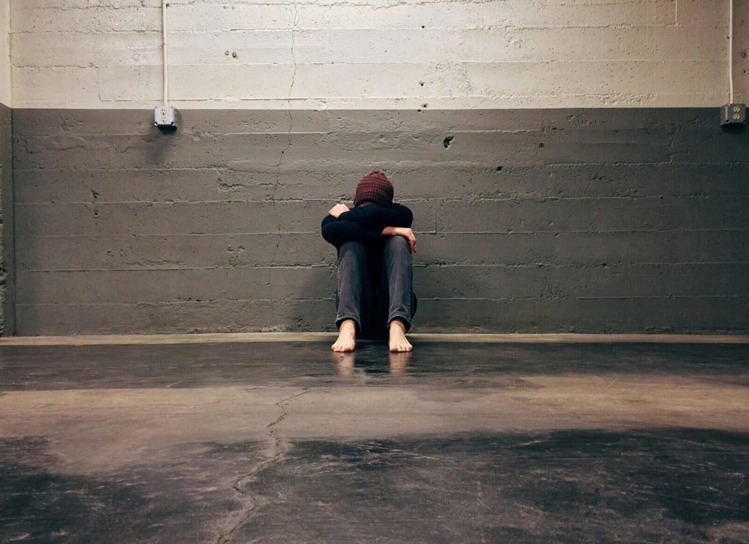 pexels-photo-236151-236151 A person sitting alone in a corner, evoking themes of solitude and emotion.