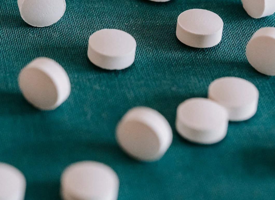 pexels-photo-5699514 Closeup of similar round white pills spilled on green tissue in random order