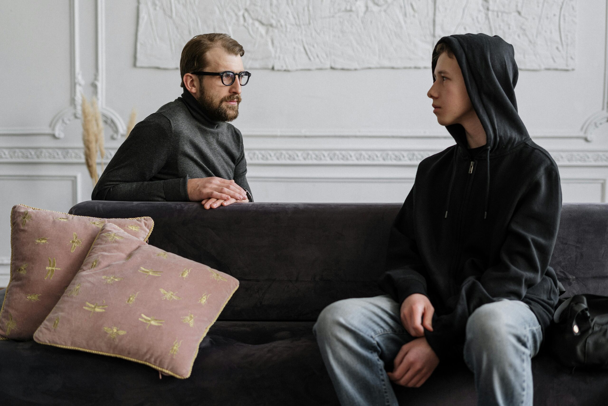 A therapist and teenager in a counseling session, indoors with a warm setting.