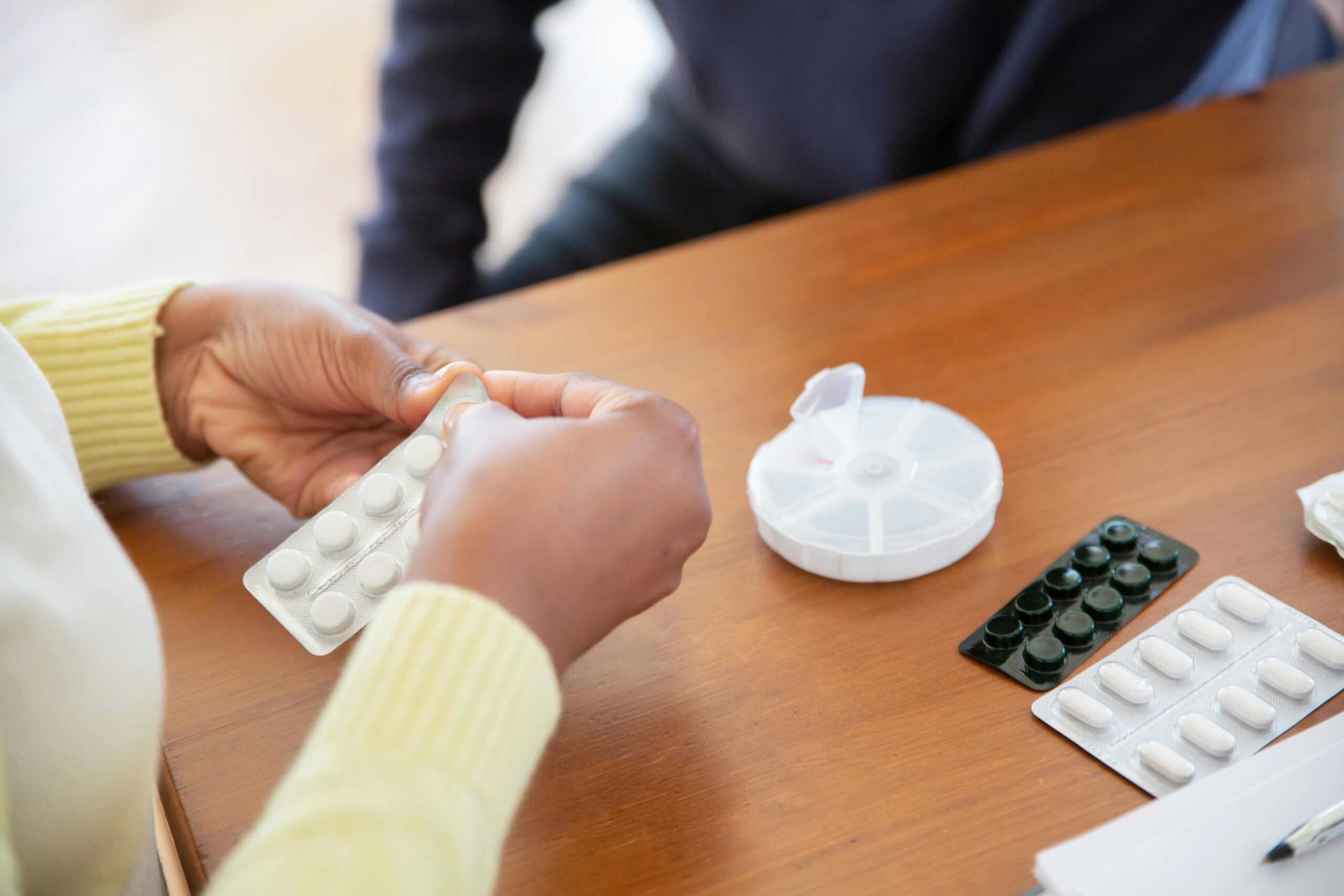 Close-up of a nurse organizing pills and medications on a table in a care setting.