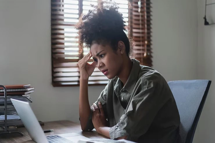 Frustrated woman looking at laptop screen experiencing adult ADHD focus challenges at Mentally Healthy Care