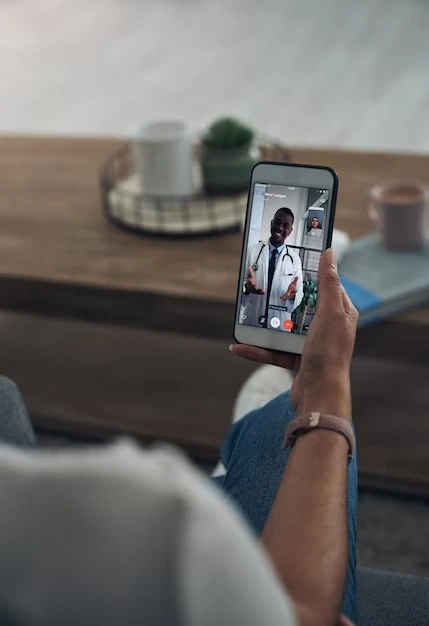 Patient holding a smartphone during an online psychiatric video call with Mentally Healthy Care in Long Beach