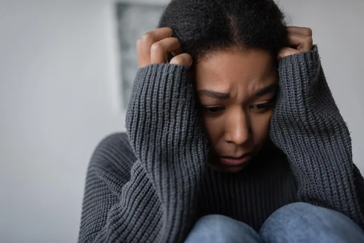 Woman holding her head in distress while experiencing depression at Mentally Healthy Care in Long Beach