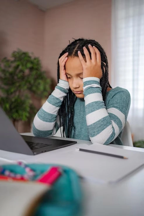Young girl feeling overwhelmed while studying at her desk due to ADHD symptoms at Mentally Healthy Care