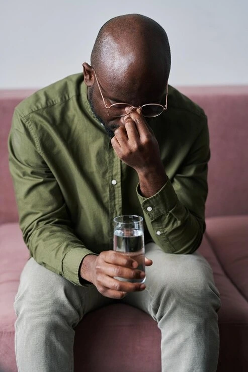Young man struggling with alcohol use disorder sitting in a room at Mentally Healthy Care in Long Beach, CA.