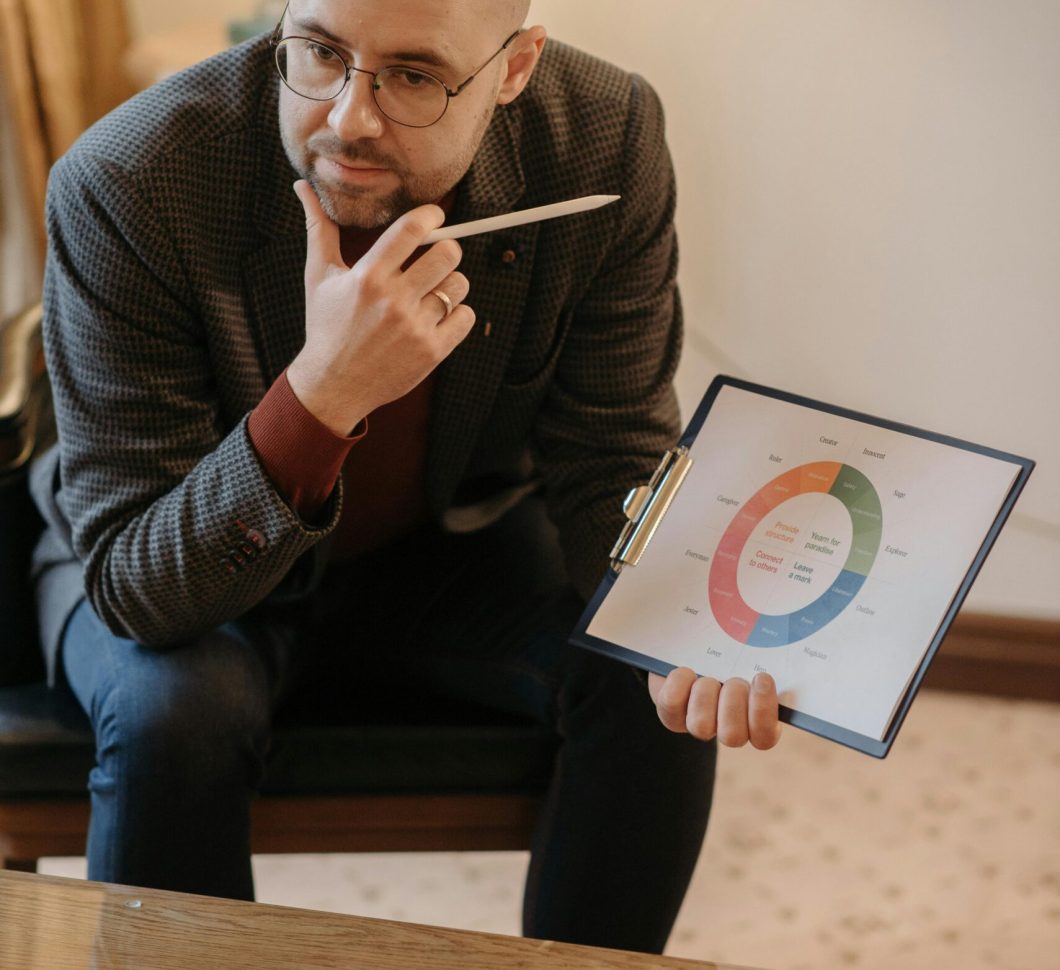 A serious counselor discusses mental health using a chart on a clipboard.